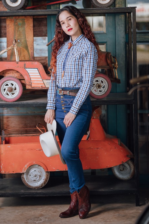 a woman wears cowboy boots with skinny jeans and a plaid shirt