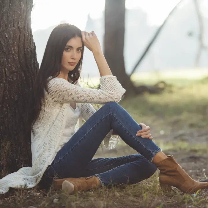 A woman wears cowboy boots with brown cowboy boots, light coat and simple tee