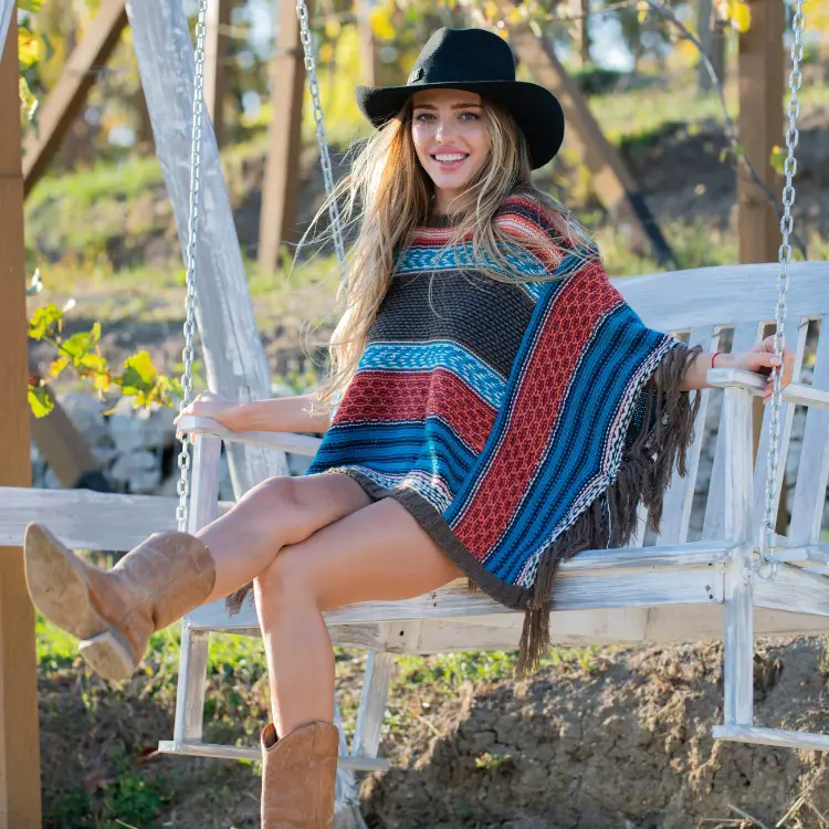 A woman wears cowboy boots with a poncho