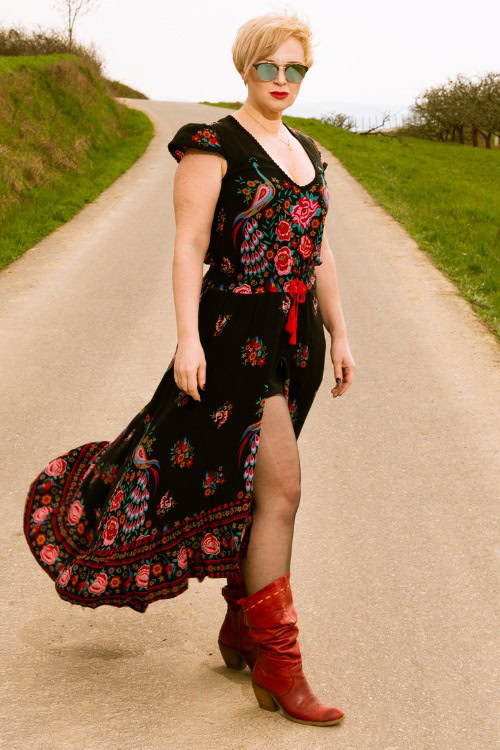 A woman wears red cowboy boots with a black floral dress