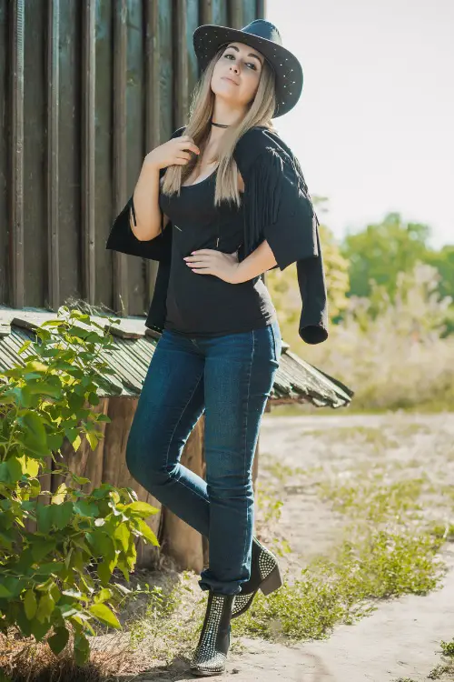 A woman wears studded cowboy boots with jeans and black top