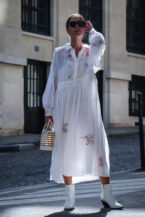 A woman wears white cowboy boots with a long white dress