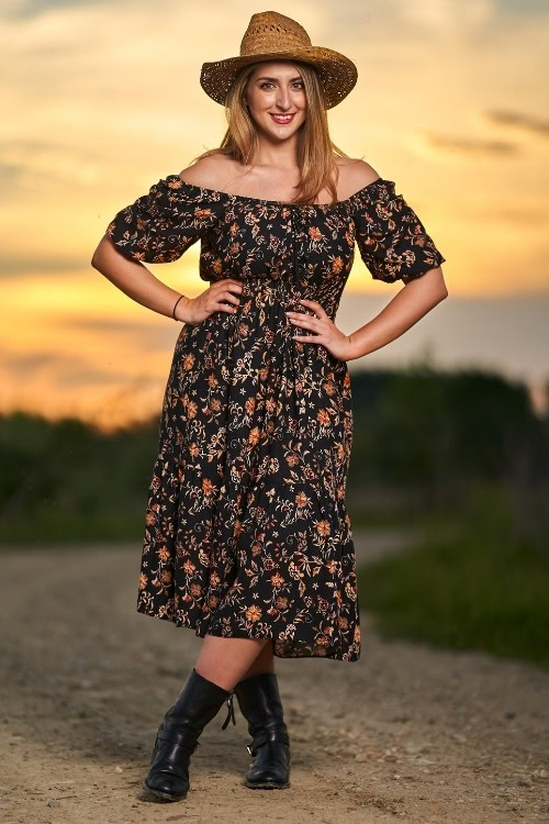 a woman wears black ankle cowboy boots with a black floral dress