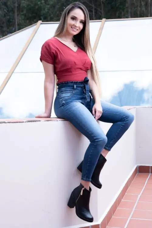 a woman wears black ankle cowboy boots with jeans and red top