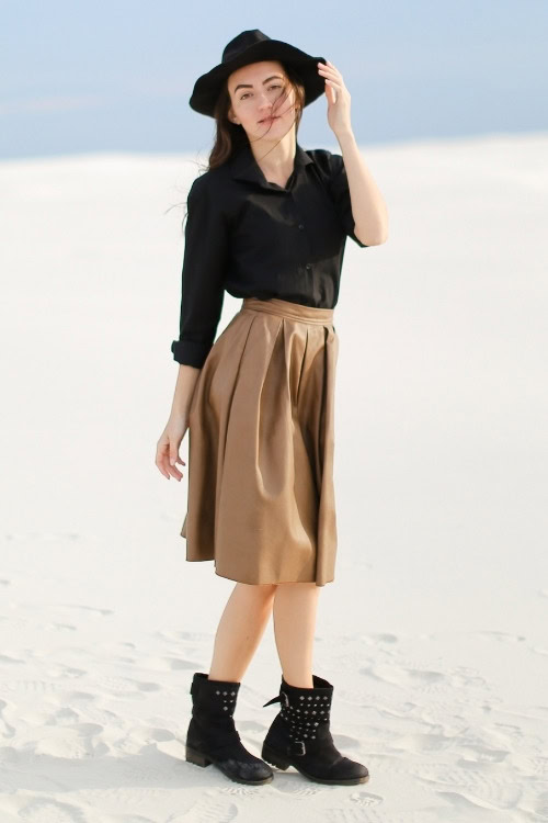 a woman wears black cowboy boots, black shirt and brown skirt
