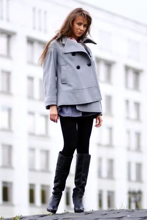 a woman wears black cowboy boots with leggings and grey blazer