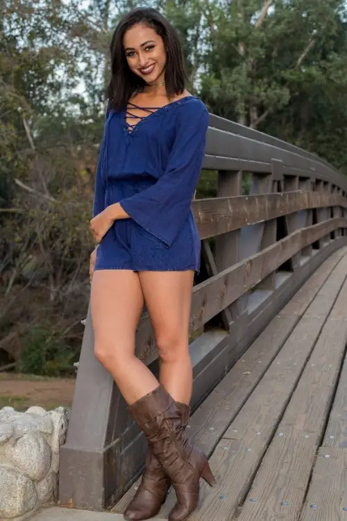a woman wears brown cowboy boots with a blue romper