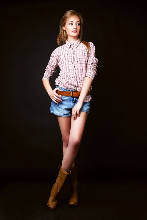 a woman wears brown cowboy boots with a shirt and shorts