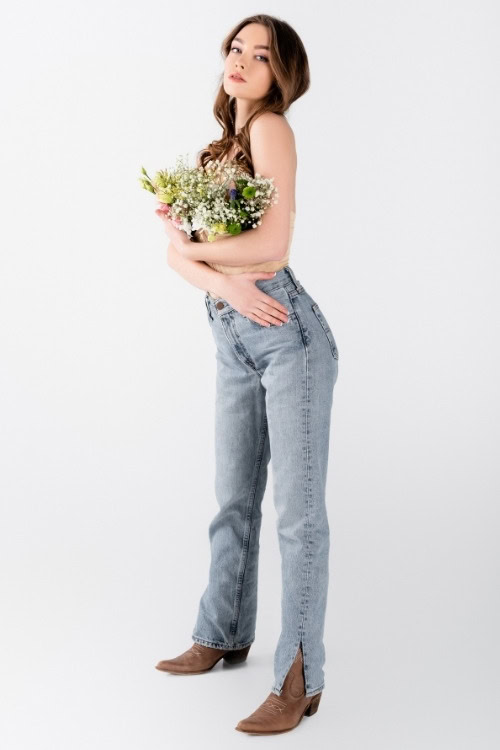a woman wears brown cowboy boots with light wash jeans huggings bouquet