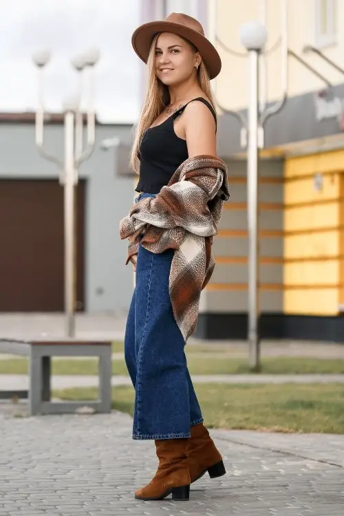 a woman wears brown cowboy boots with wide jeans and a black top