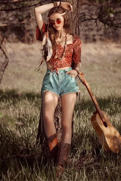 a woman wears cowboy boots with a boho top and shorts