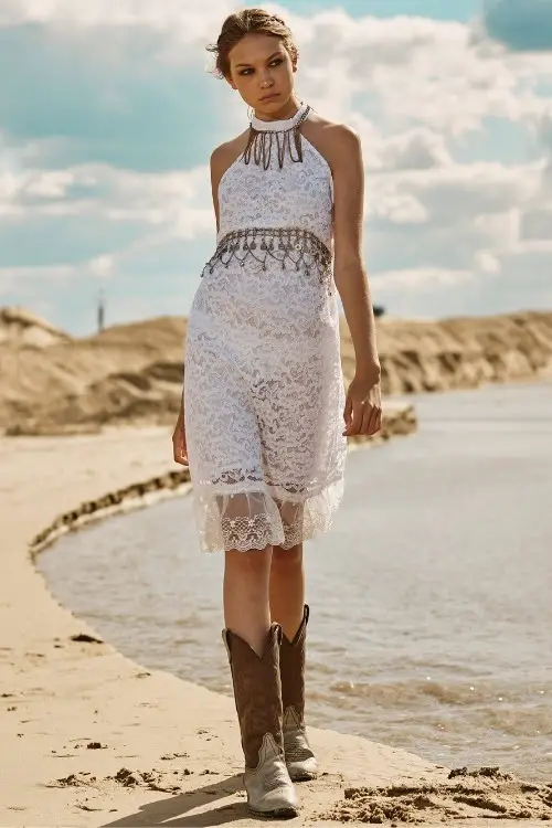 a woman wears cowboy boots with a short lace dress