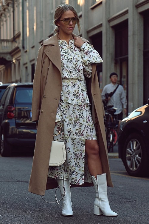a woman wears white cowboy boots with tiered dress and trench coat