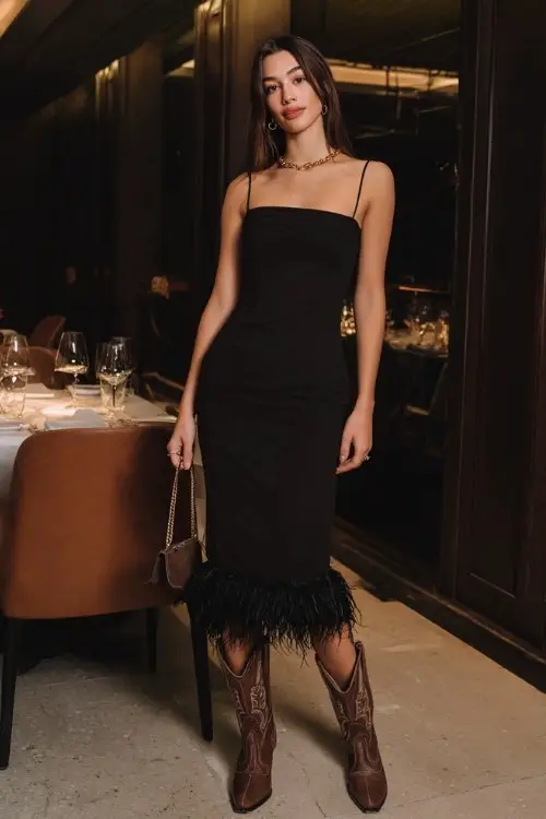 a woman in a fitted black midi dress with feather-trimmed hem and brown cowboy boots at a dinner date, styled with minimalist gold jewelry, sleek straight hair, elegant makeup