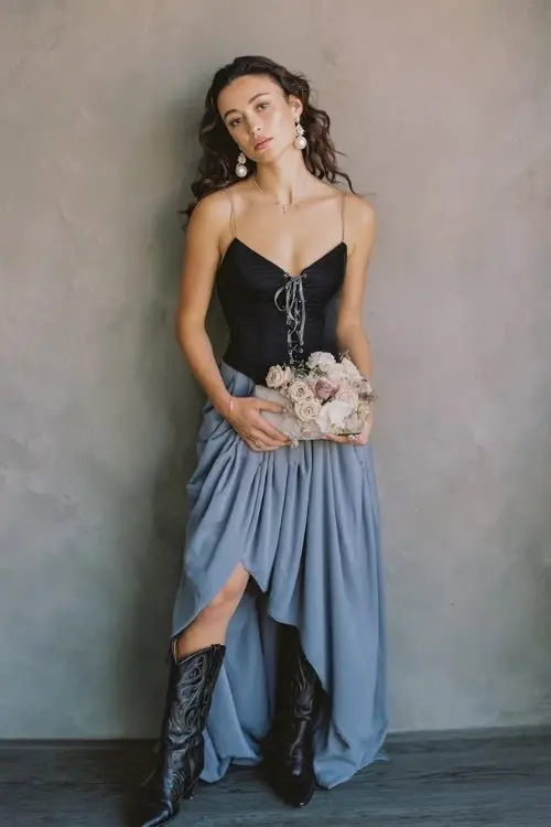 a woman in a romantic lace-up back fancy dress with a flowing skirt and cowboy boots at an engagement party