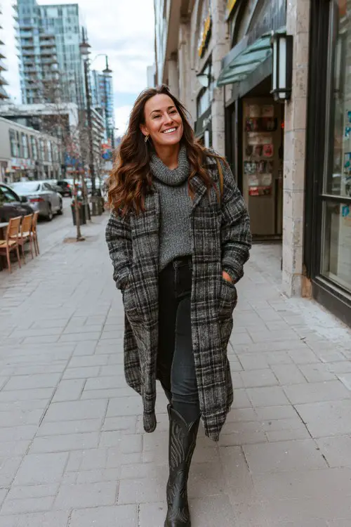 A curvy woman wears black cowboy boots with dark skinny jeans, a chunky gray turtleneck, and a long plaid coat (2)