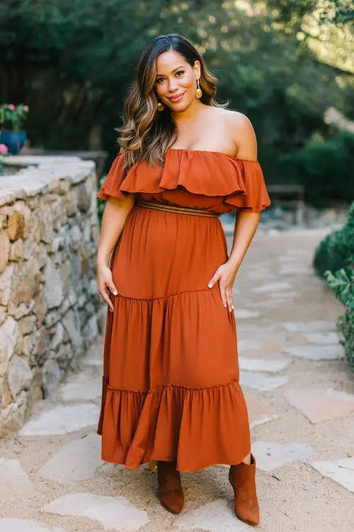 A curvy guest in a burnt orange off-the-shoulder maxi dress with a tiered skirt and belted waist, paired with heeled boots and soft waves in fall wedding (2)