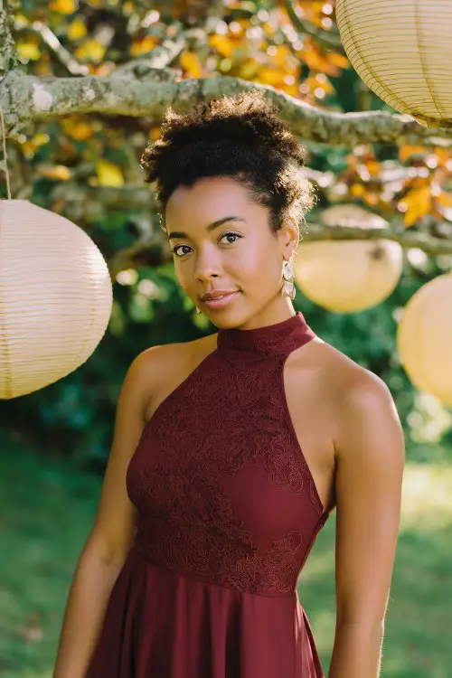 A woman in a burgundy high-neck midi dress with an asymmetrical hem and embroidered bodice