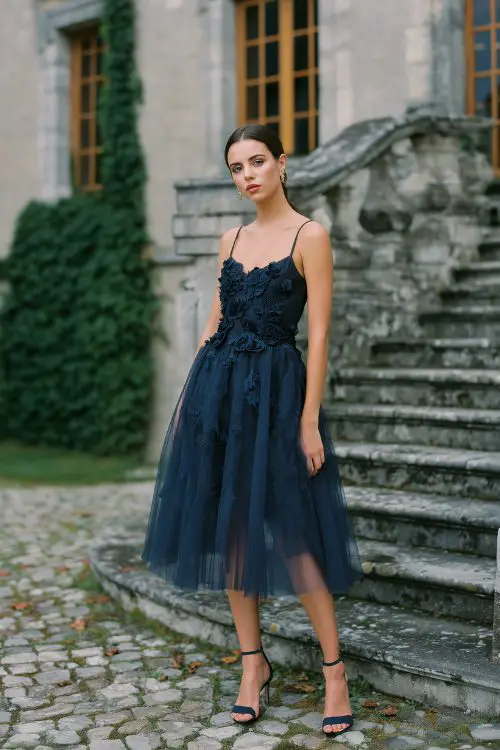A woman in a navy tulle dress with floral appliqué and ankle-strap heels