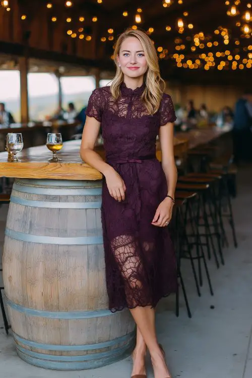 A woman over 30 in a dark plum lace midi dress with a scalloped hem and peep-toe heels