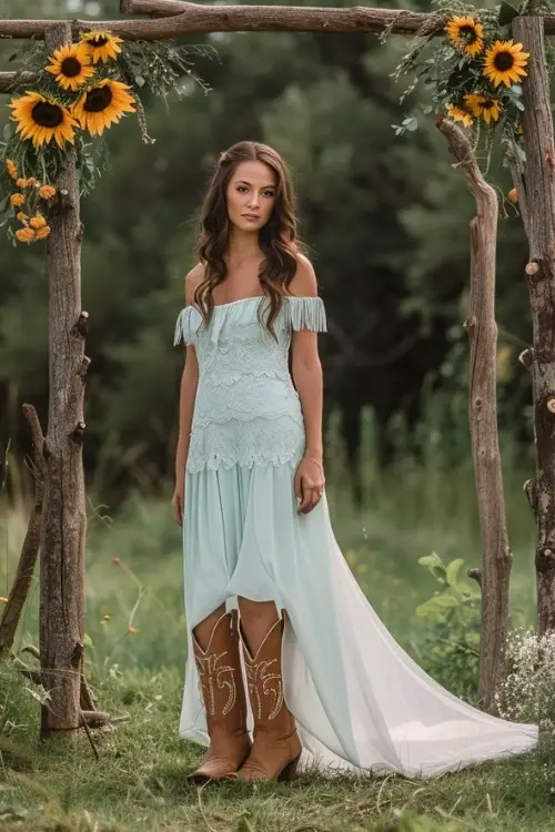 A woman wears a light blue long bridesmaid dress with brown cowboy boots