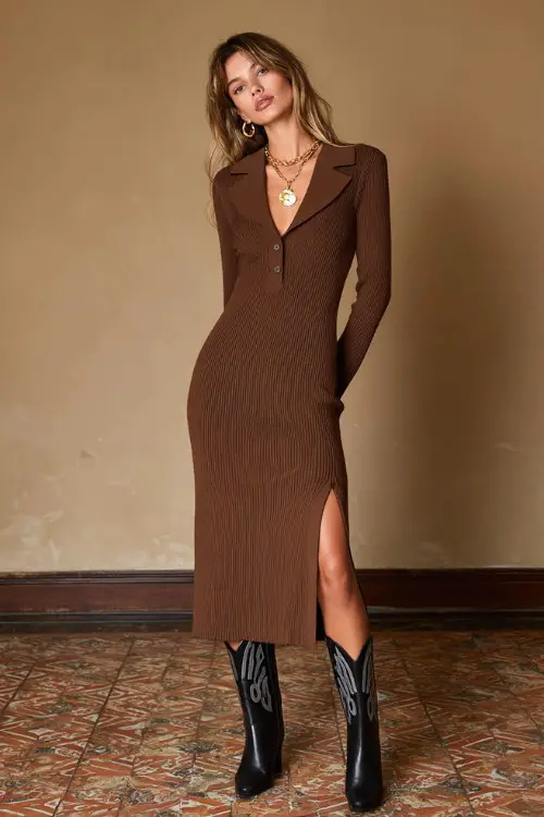 A woman wears a mocha ribbed knit midi dress with a structured collar and a front slit, paired with black heeled cowboy boots and a gold pendant necklace