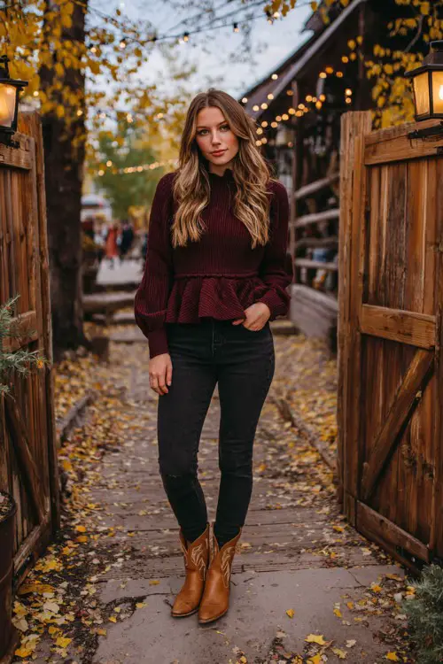 A woman wears dark-wash jeans, a burgundy peplum sweater, and caramel-colored cowboy boots