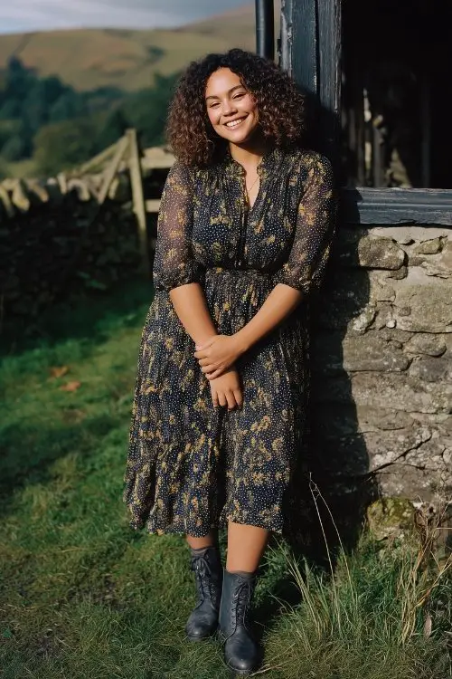 A curvy woman wears a navy and gold leaf-print A-line midi dress with sheer sleeves and ankle boots