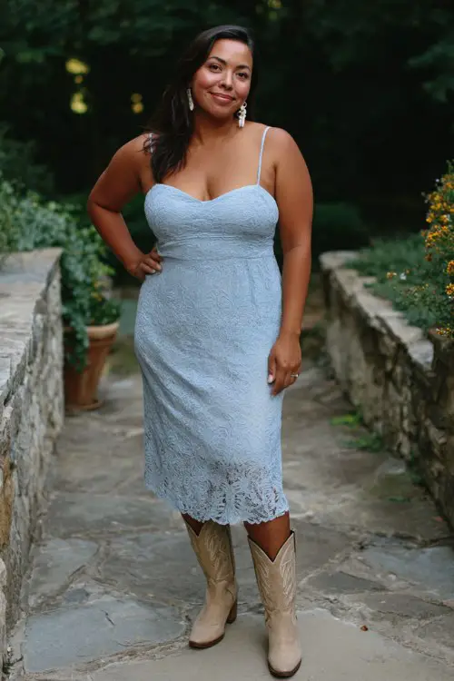 A plus-size woman wears a pale blue lace dress with beige cowboy boots and pearl earrings