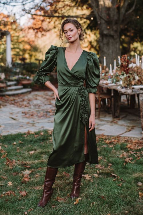 A woman over 30 wears a forest green satin wrap dress with dramatic puff sleeves and delicate floral appliqués, styled with chocolate brown knee-high boots (2)