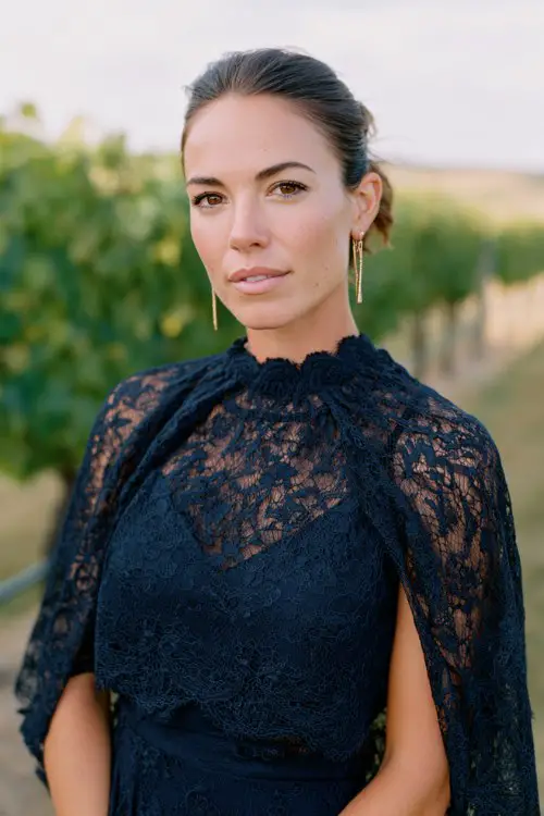 A woman over 30 wears a navy lace short dress featuring a high neckline, fitted bodice, and subtle scalloped hemline
