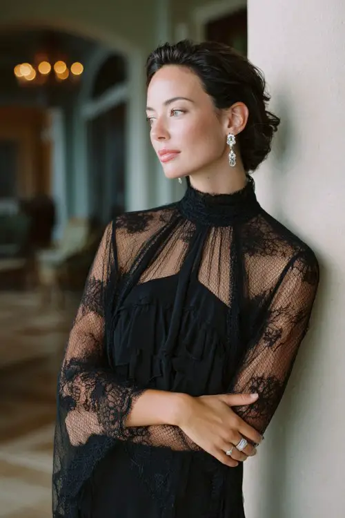 A woman over 40 wears a black lace midi dress featuring a high neckline, sheer lace sleeves, and layered chiffon panels