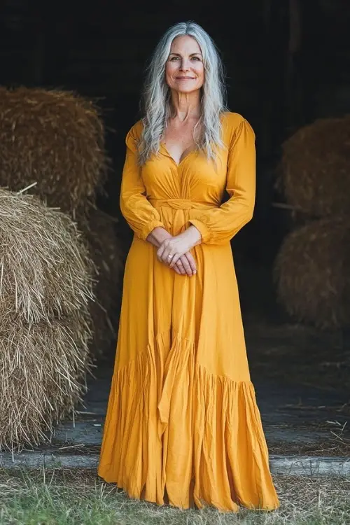 A woman over 50 wears a mustard wedding guest dress with long sleeves