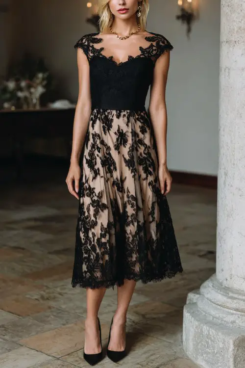 A woman wears a black lace dress featuring delicate floral appliqué over a soft neutral-toned lining, cap sleeves, and a gently pleated skirt
