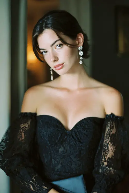 A woman wears a black lace midi dress featuring sheer puff sleeves, a scalloped sweetheart neckline