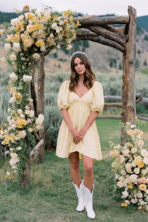 A woman wears a flowy pastel yellow dress with white cowboy boots and a delicate headband