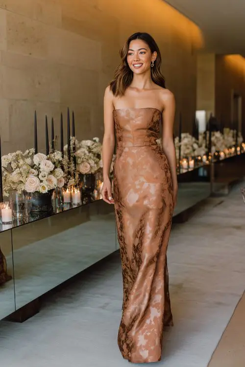 A woman wears a muted copper brocade dress with a square neckline and subtle floral pattern woven into the fabric