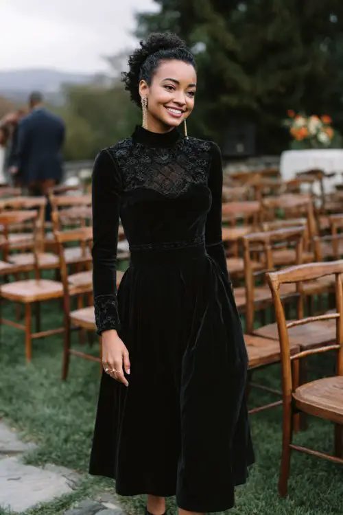 a petite woman in a black velvet fit-and-flare dress with embroidered bodice and high neckline