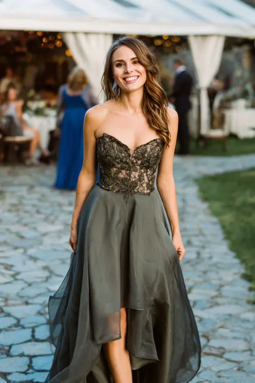 a petite woman in a dark sage high-low dress with embroidered bodice and sheer overlay
