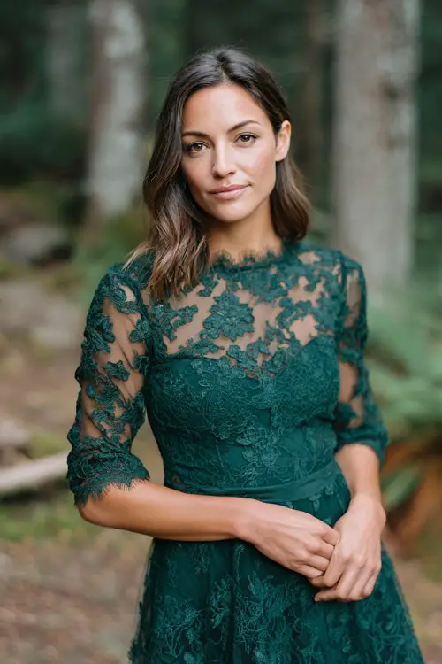 a petite woman in a forest green lace knee-length dress with scalloped edges and sheer sleeves