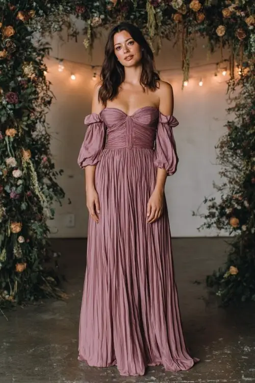 a woman over 30 in a dusty rose off-shoulder gown with a pleated skirt