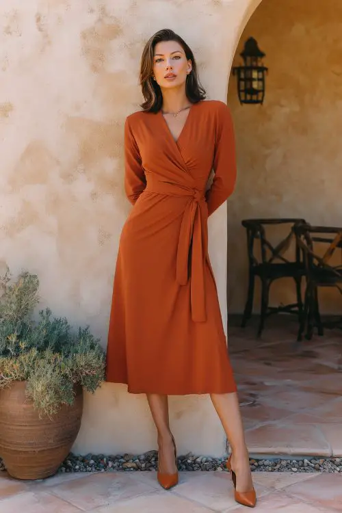 a woman wears a rust orange wedding guest dress