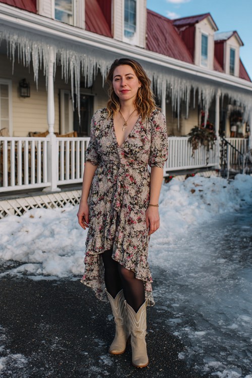 A curvy woman wears a floral midi dress with a ruffle hem, black tights, and beige cowboy boots