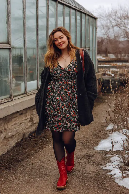 A woman in a deep green off-the-shoulder dress, slouchy brown cowboy boots, and a luxurious velvet wrap