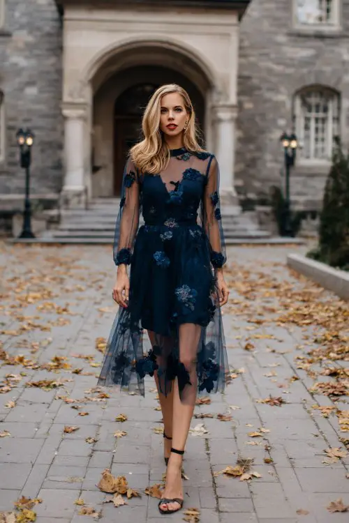A woman over 30 wears a navy tulle midi dress with embroidered floral details 