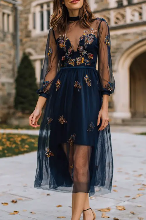 A woman over 30 wears a navy tulle midi dress with embroidered floral details