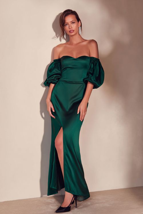 A woman wears a deep emerald satin long gown with dramatic off-shoulder sleeves and elegant black heels