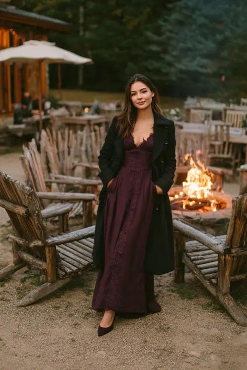 A woman wears a long plum dress with lace sleeves, dark coat, and pointed heels