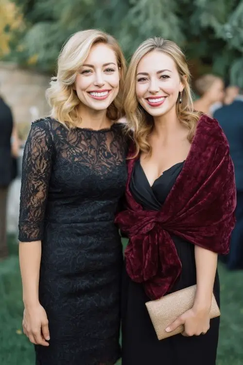 two women wear black wedding guest dresses, one covered with burgundy shawl (1)
