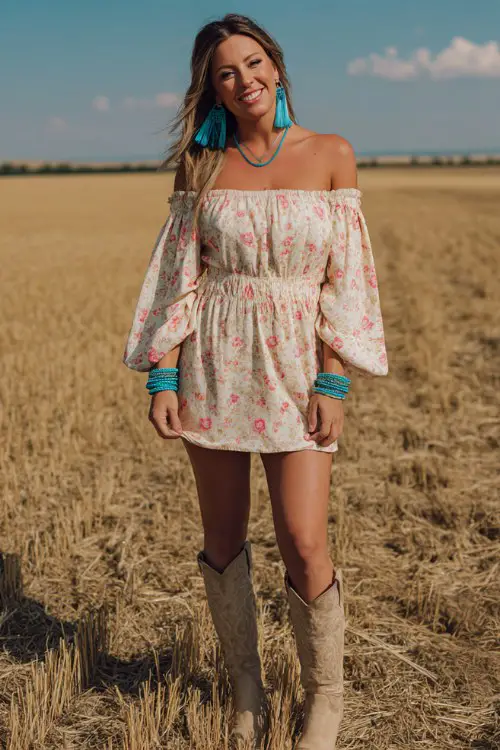 A beautiful woman standing in an open golden field wearing an off-shoulder floral mini dress in soft cream with pink rose print and flowy bell sleeves